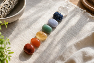 Seven chakra stones arranged from red to violet on a neutral surface