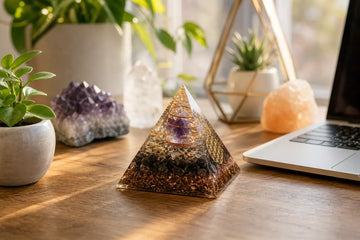 Orgonite pyramid on a sunlit desk with plants and calm home decor